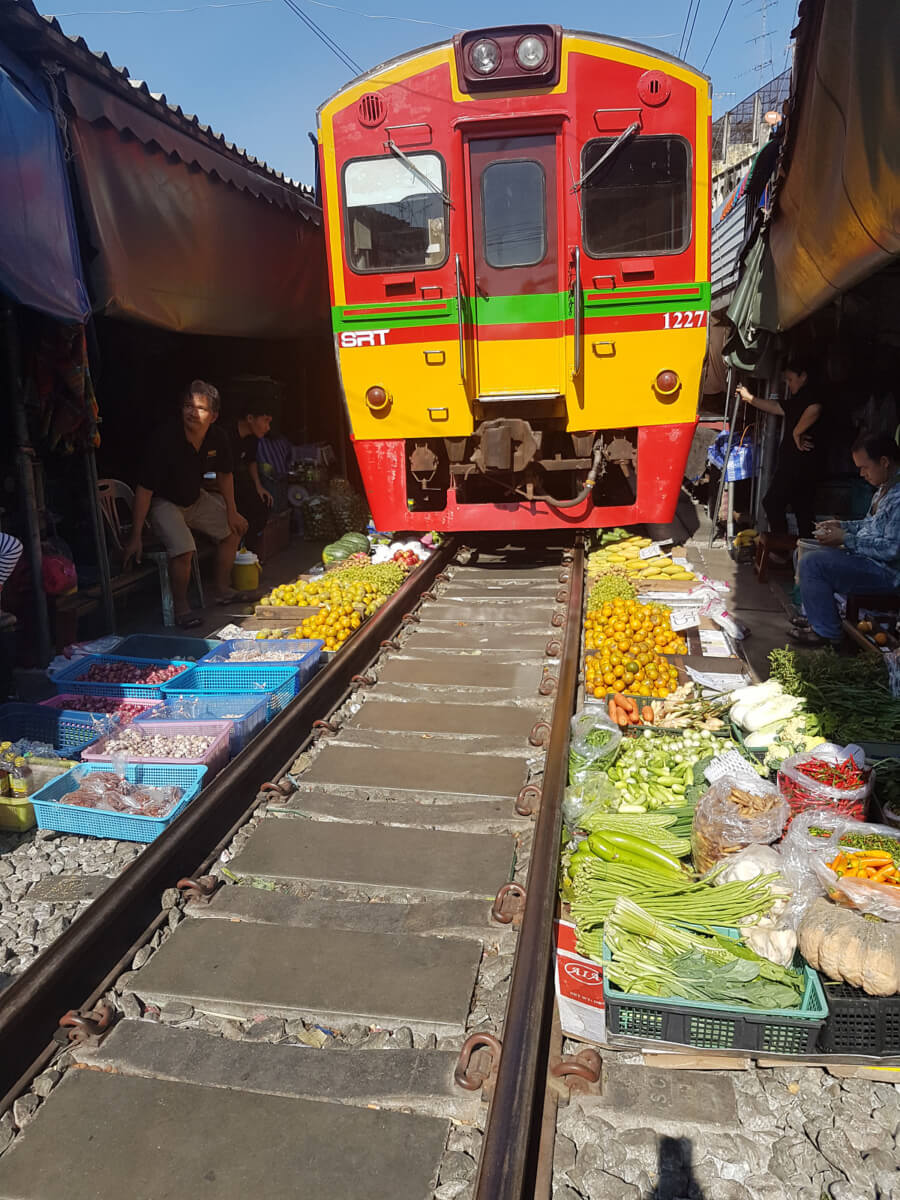 Vlak jede těsně nad ovocem a zeleninou, Maeklong Railway Market, Bangkok